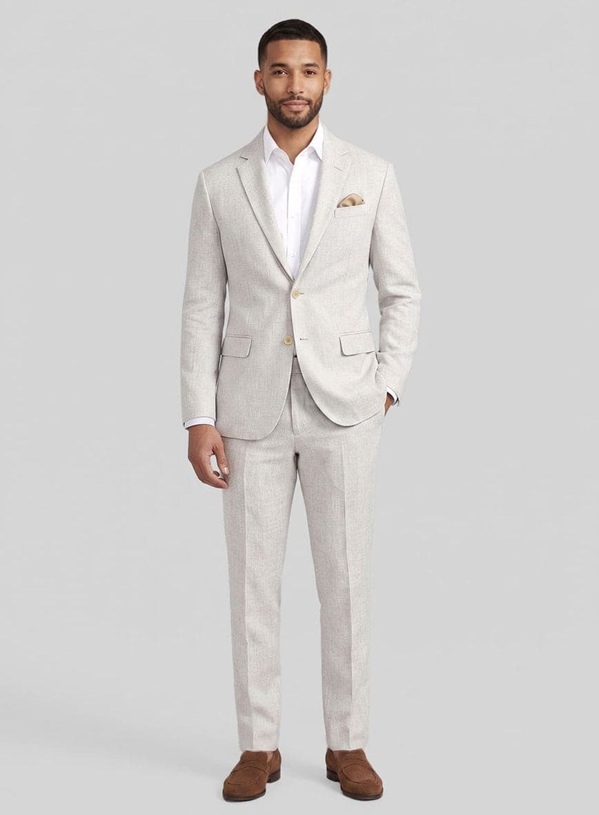 A man wearing a light beige linen two-piece suit with a white shirt and brown loafers