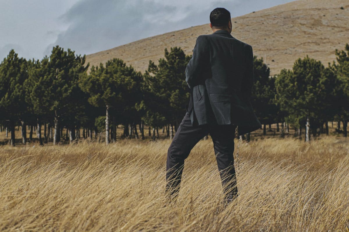 Rear view of a man in a suit jacket showing the back drape, center seam, and vents