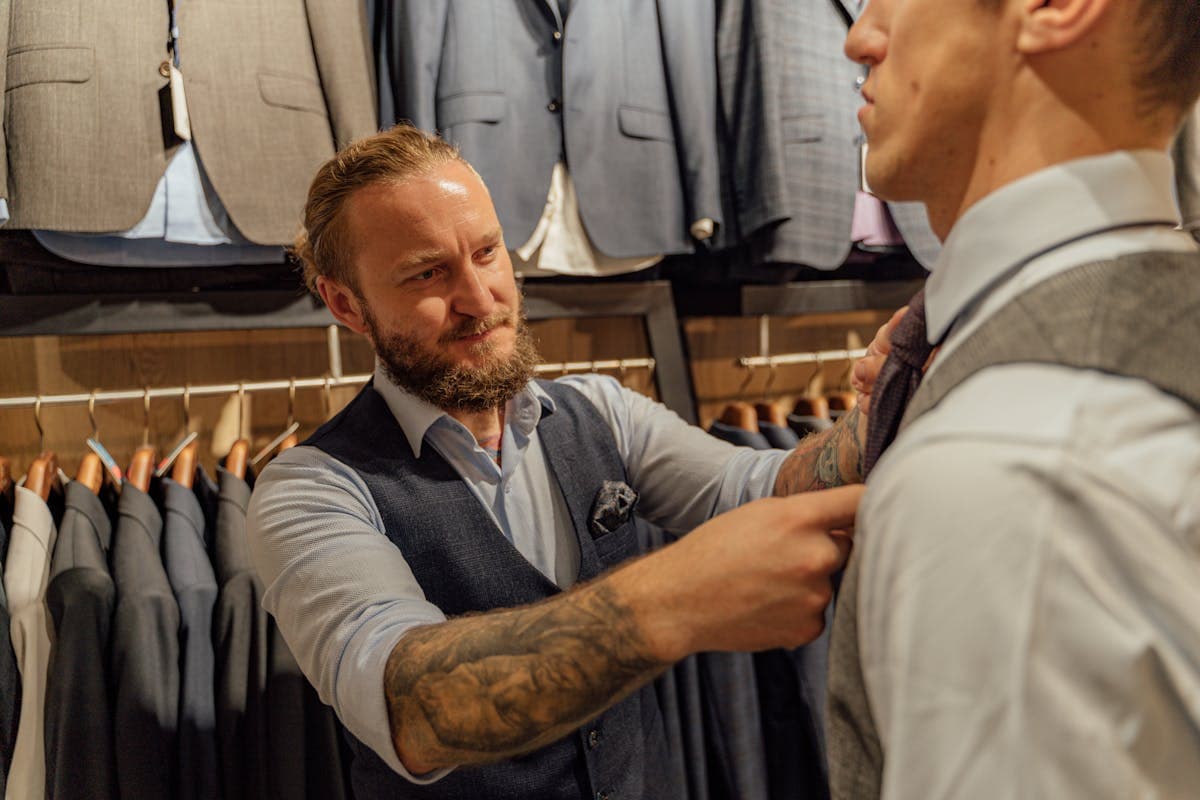 Tailor's hands pinning and marking a suit jacket for alteration with chalk and pins