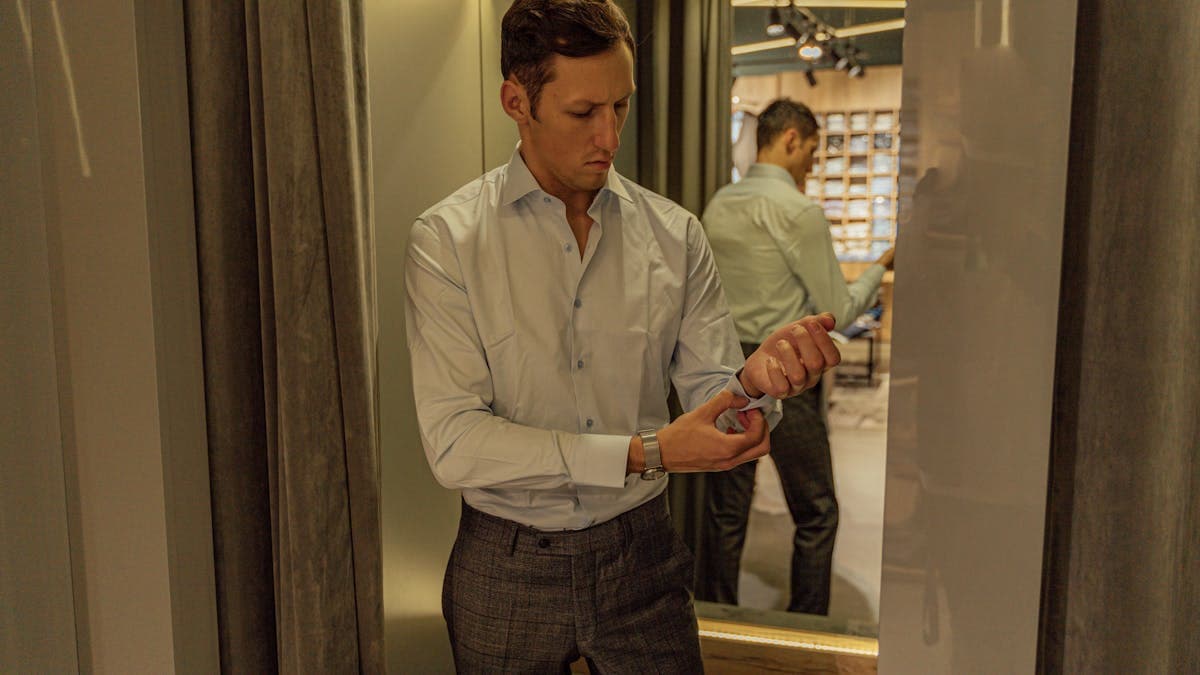 Man looking at himself in a mirror while wearing a well-fitted custom suit