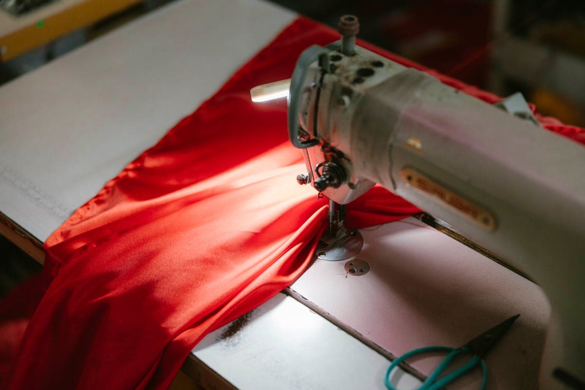 Tailors at work in a busy tailoring workshop with fabric bolts and sewing machines