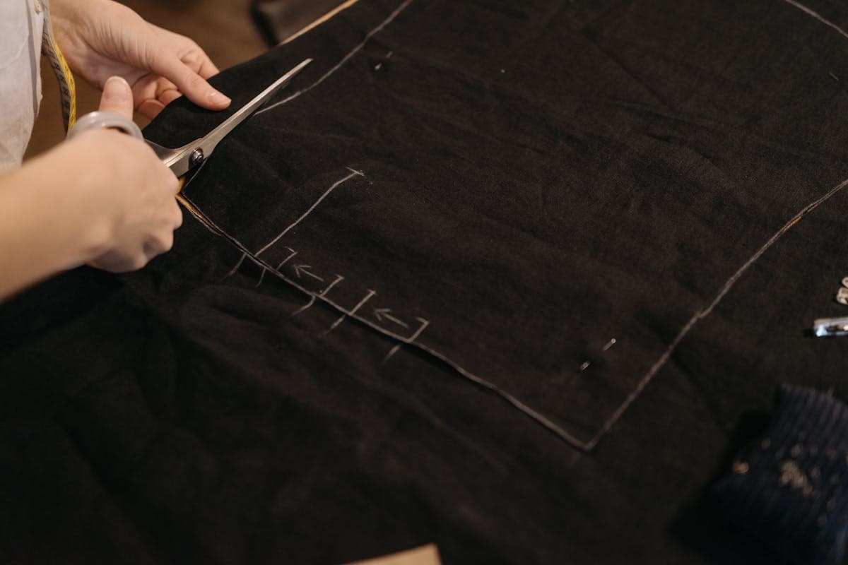 Tailor cutting suit fabric along a paper pattern on a cutting table