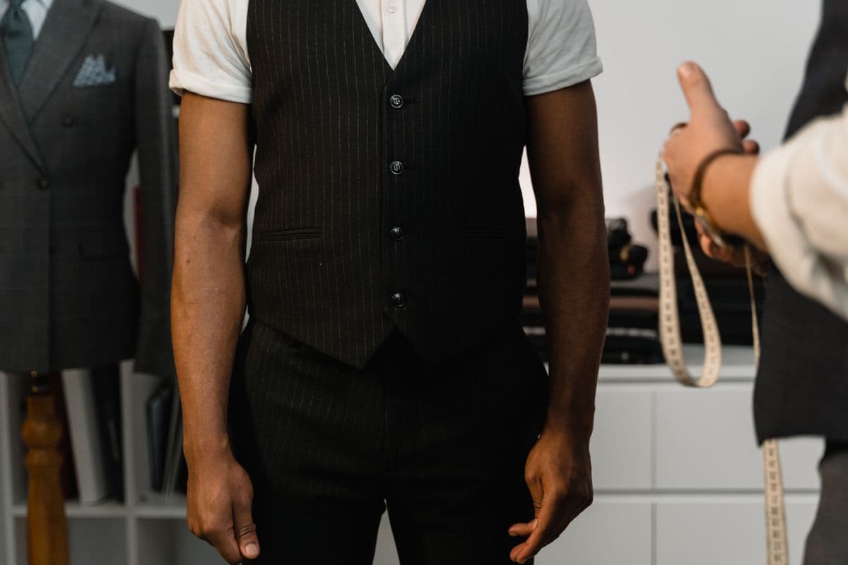 A well-fitting suit jacket laid flat on a table with a tape measure across the shoulder seam, used as a reference for sizing