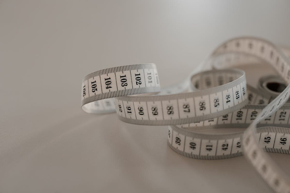 Close-up of a soft fabric sewing tape measure coiled on a wooden tailor's table at a Hoi An tailor