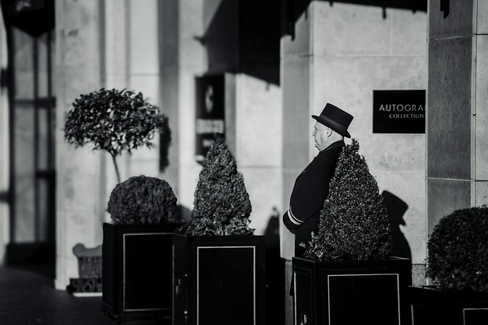 Doorman in formal attire at the entrance of a luxury boutique hotel — custom hotel front desk uniforms and bellman jackets tailored by Nathan Tailors in Hoi An