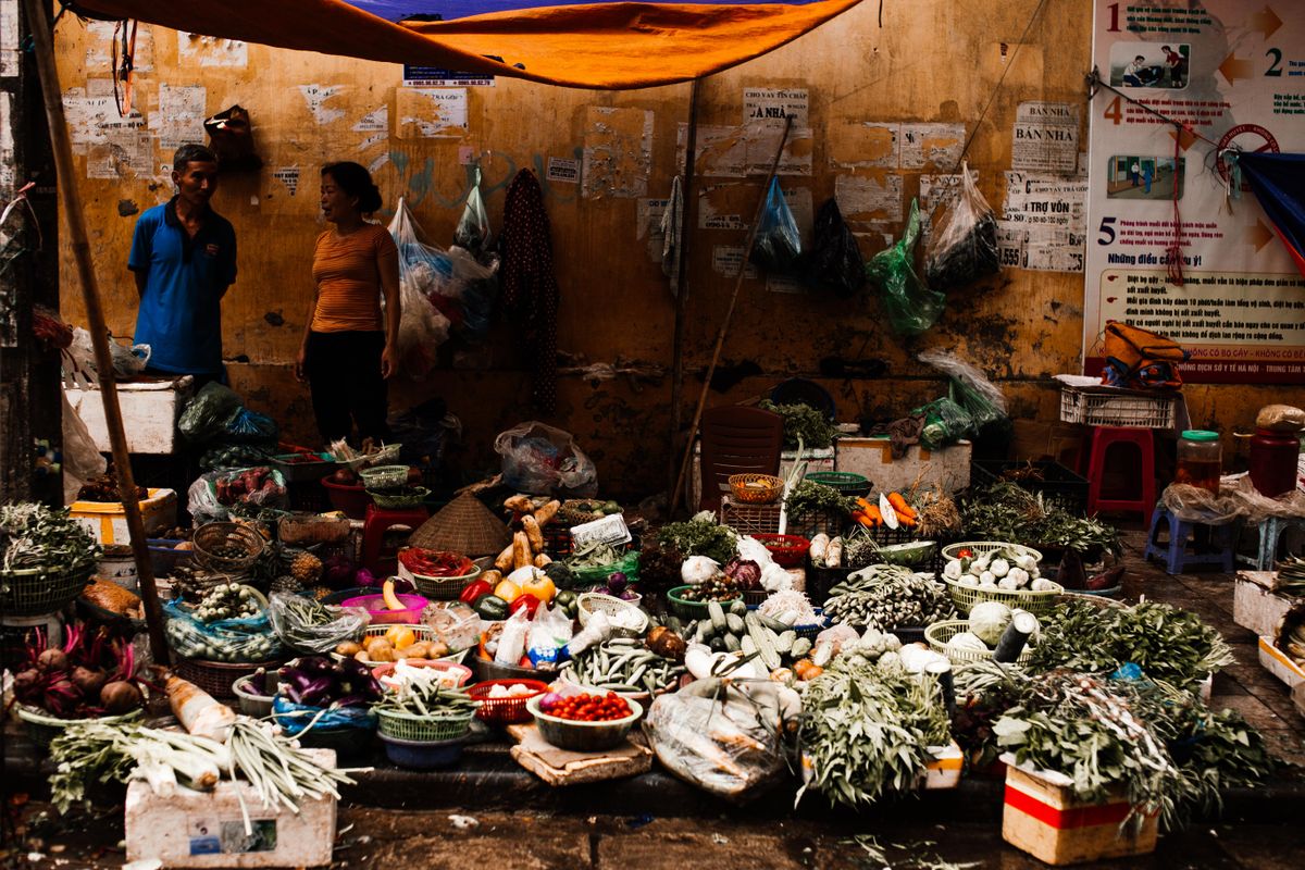 Early morning at Hoi An Central Market with vendors stacking fresh herbs and produce into pyramids