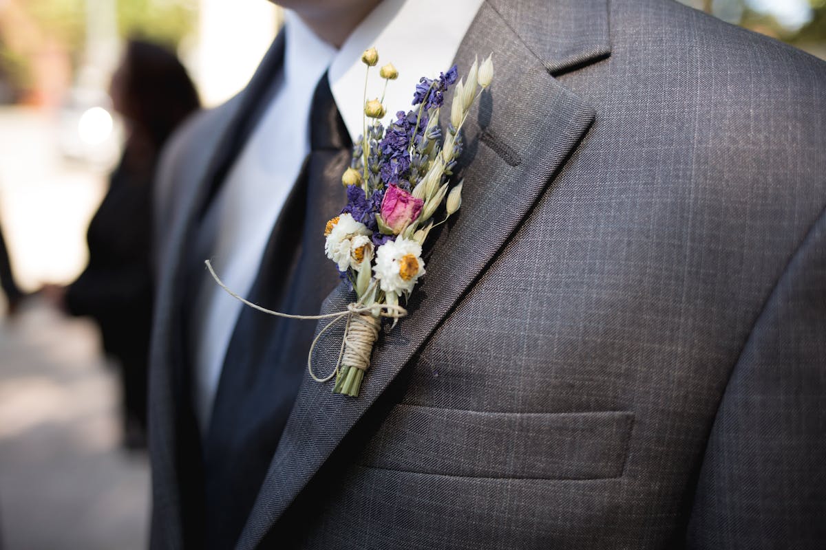 Man in a light linen suit at an outdoor summer garden wedding, relaxed and weather-appropriate in warm sunshine