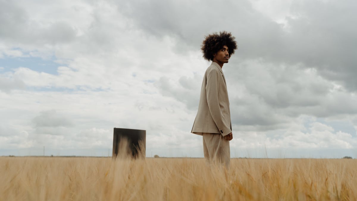 Man wearing a relaxed beige linen suit in a summer meadow -- the ideal warm-weather fabric that breathes and drapes beautifully