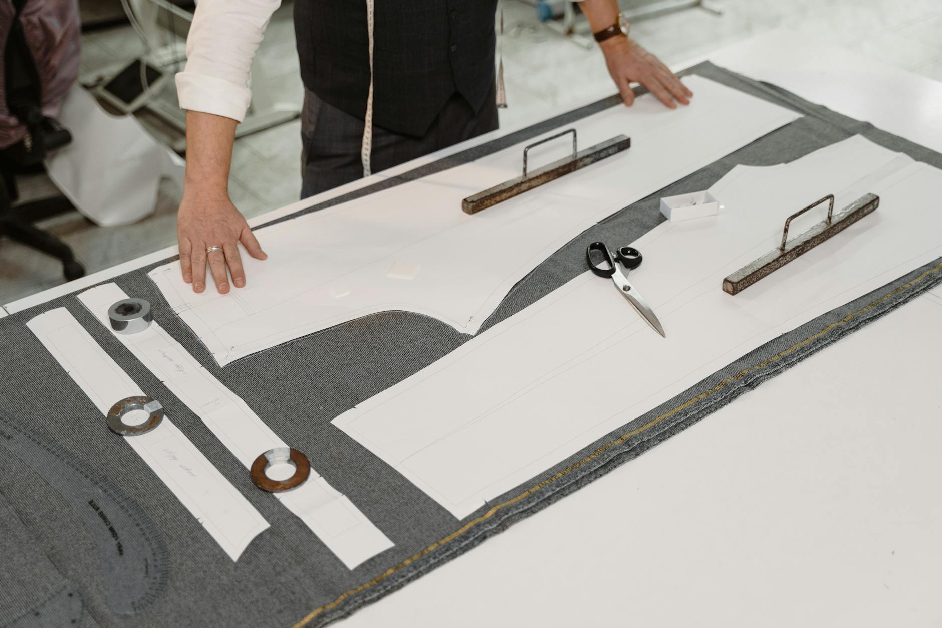 Tailor's workshop with bolts of fabric, hand-cut patterns, and the quiet machinery of bespoke tailoring -- the inputs we tried to teach a language model to see