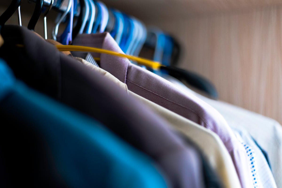 A row of finished custom suits in different fabrics and colors hanging on a tailor's rack
