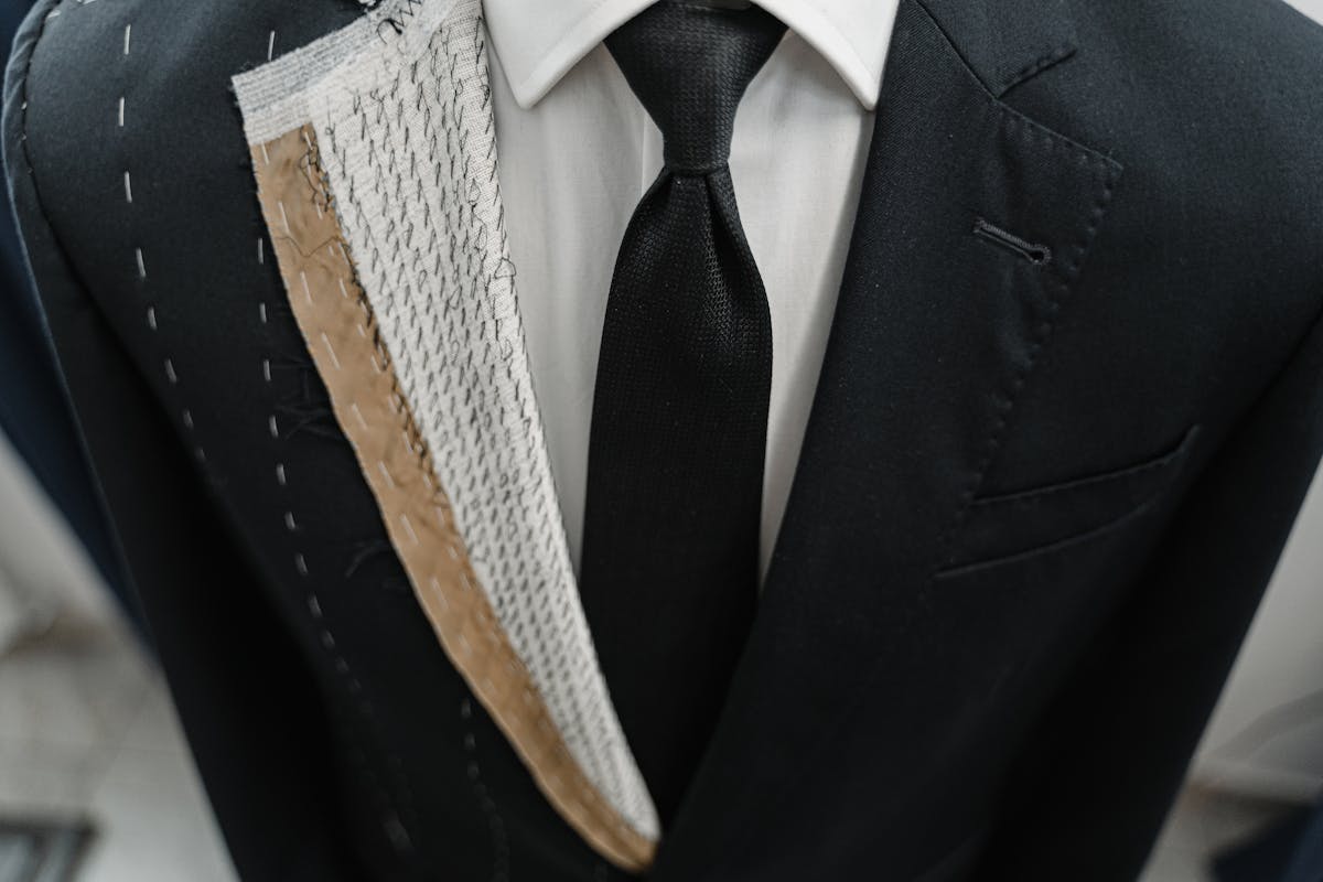 Tailor hand-stitching the interior canvas of a suit jacket at a workbench