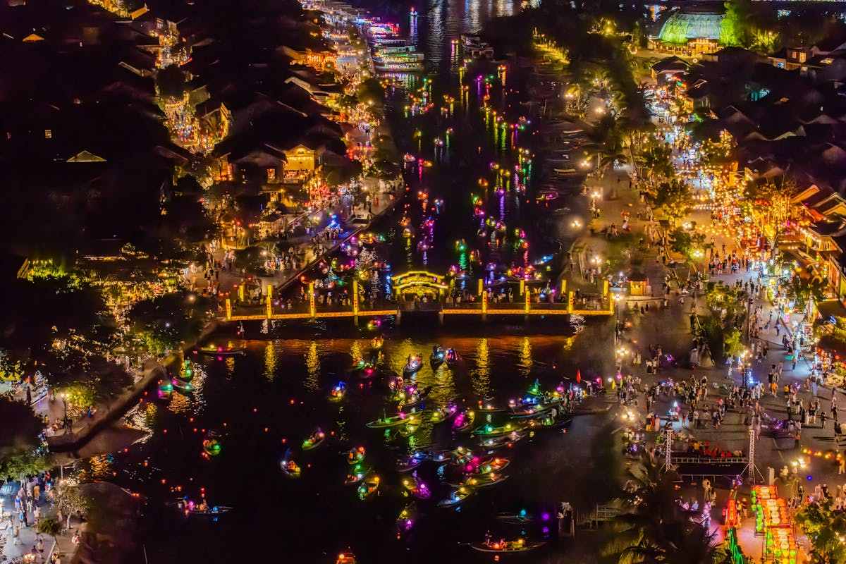 Silk lanterns glowing over the streets of Hoi An Old Town at night, reflected on the Thu Bon River