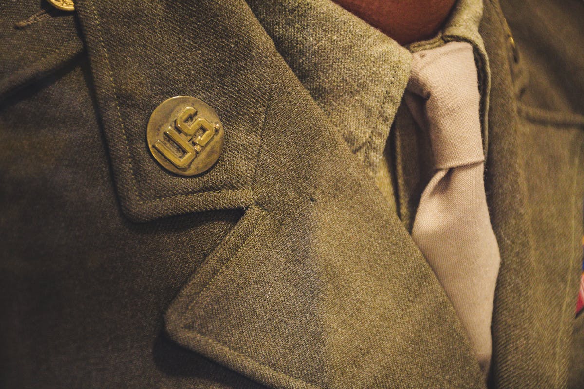 Close-up of a silver and turquoise bolo tie worn over an open-collar linen shirt