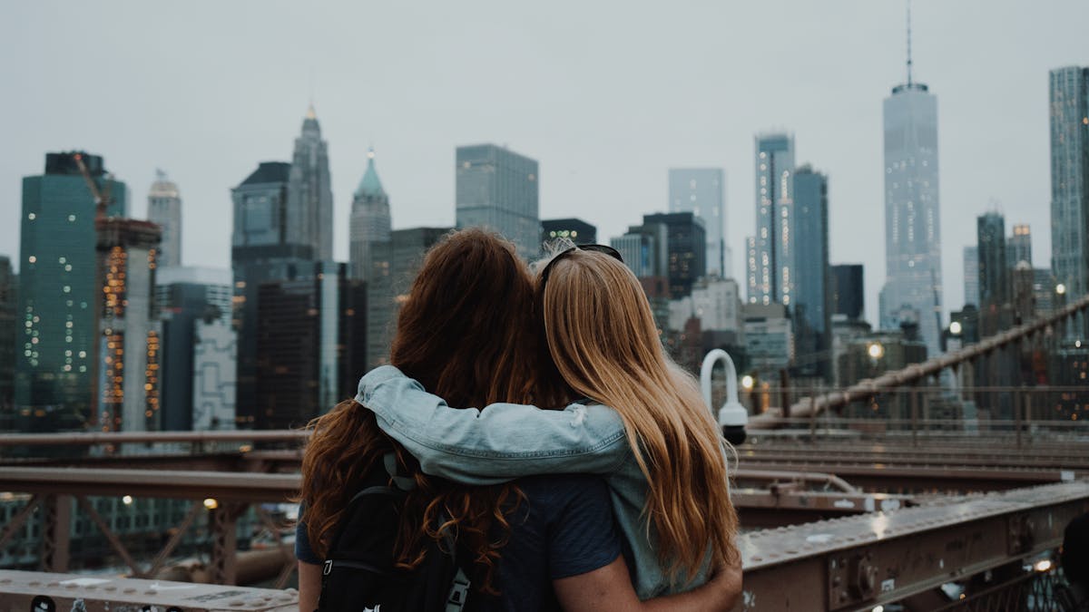 Couple on the Brooklyn Bridge with the New York City skyline in the background, planning their wedding together