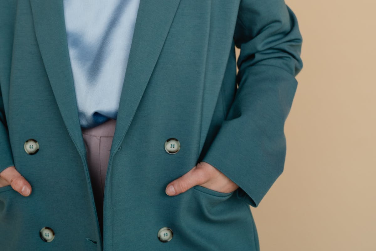 Close-up of a tailored double-breasted jacket front showing two columns of buttons, peak lapel and a clean modern shoulder line