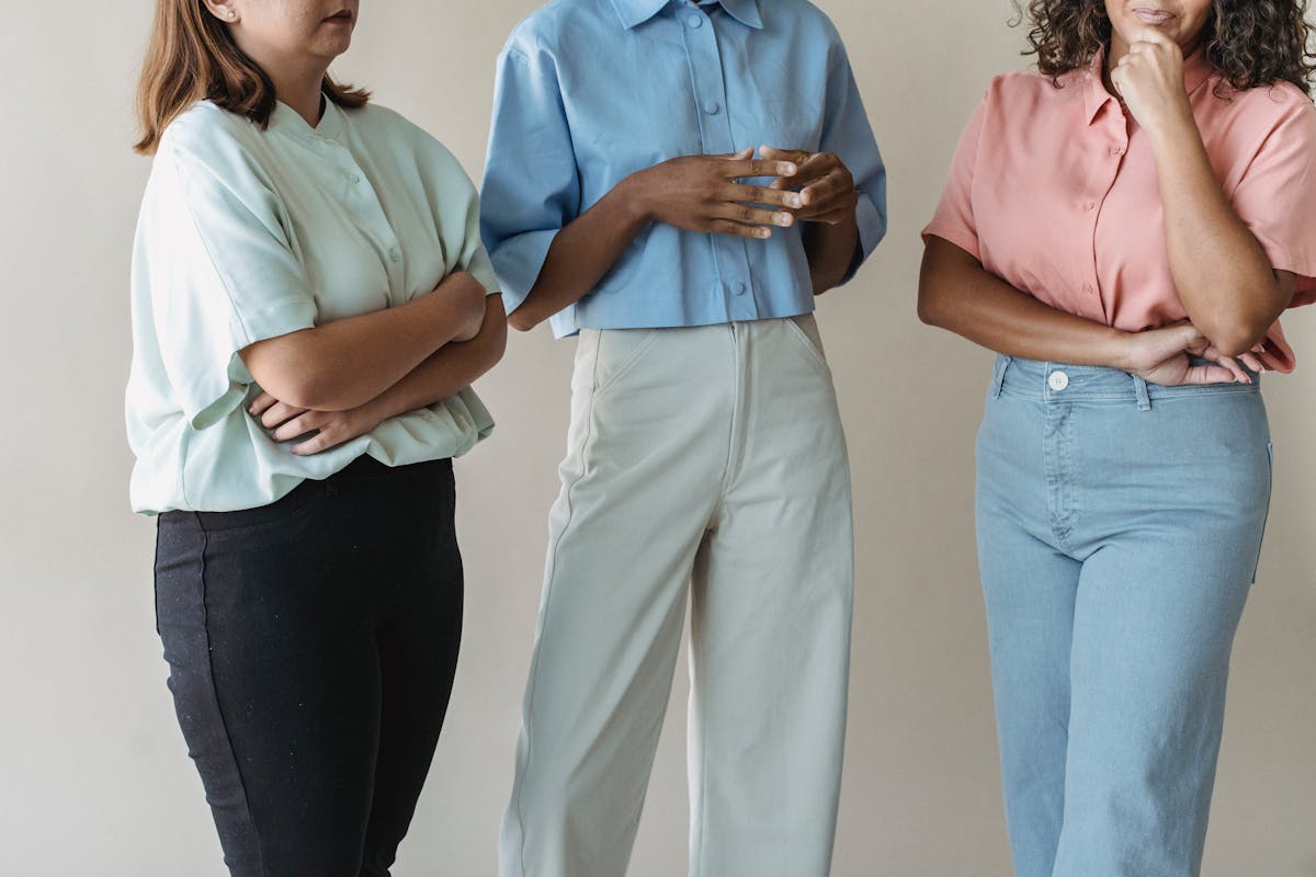 Three or four well-dressed twenty-somethings in distinct muted tailored looks standing together, illustrating one shared vocabulary in different executions
