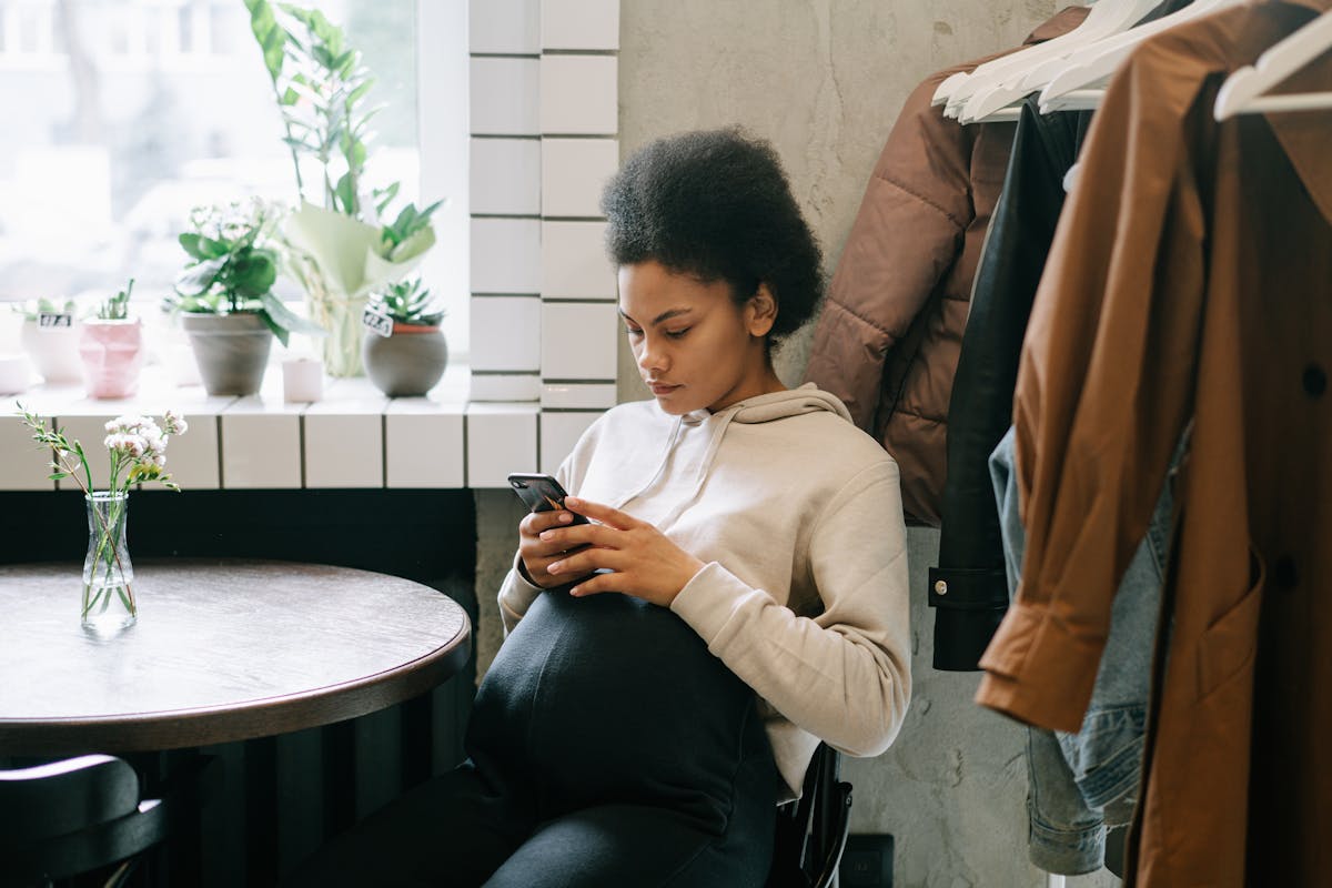 Group trip coordinator typing a message on a phone while reviewing notes at a cafe table