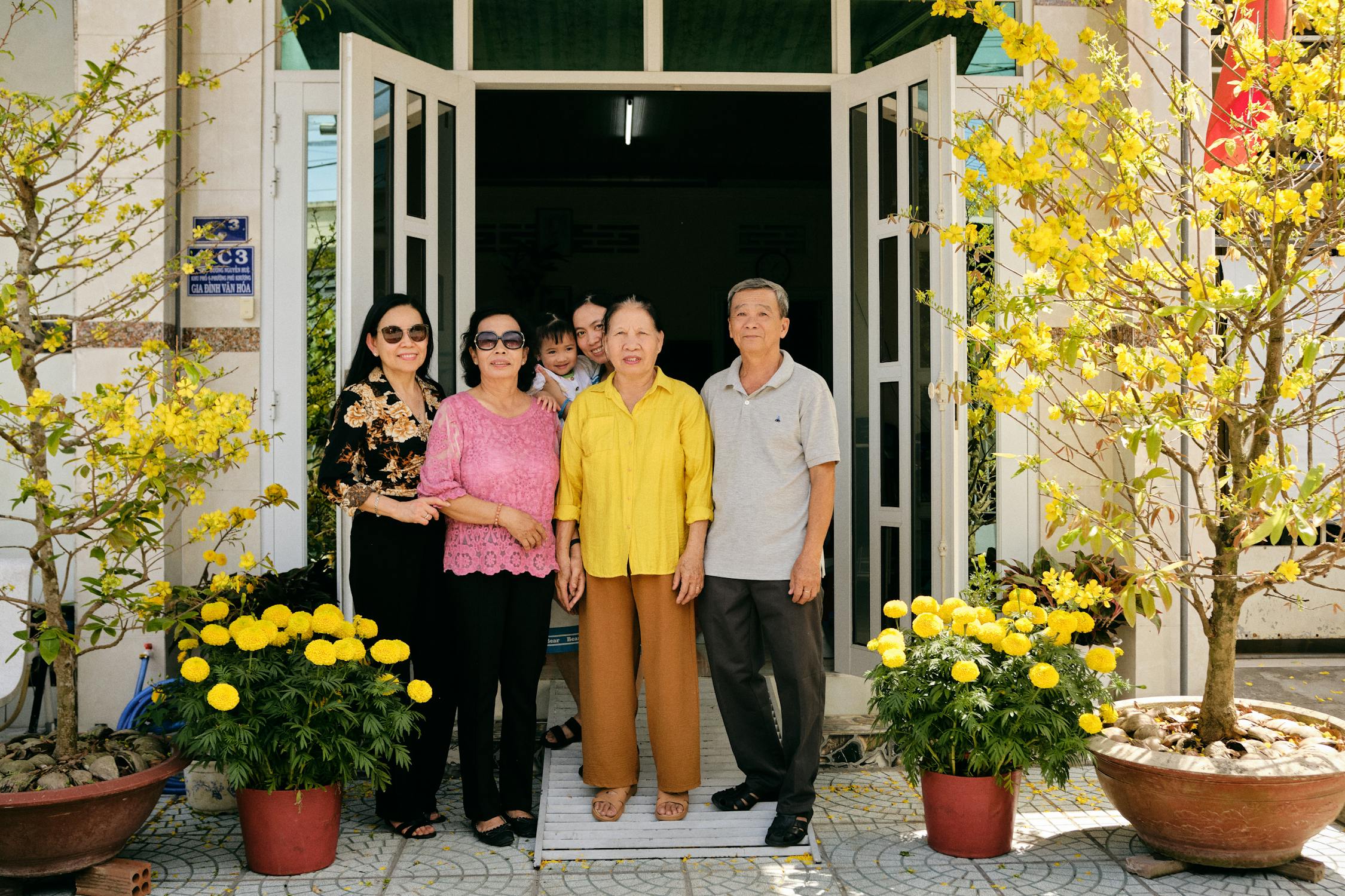 A large family group browsing fabrics together inside a tailor shop in Hoi An, Vietnam