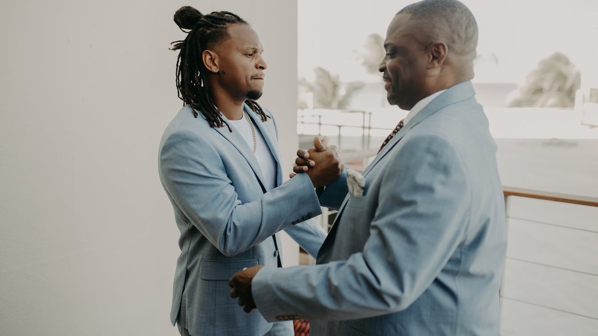 Father and son sharing a warm moment together, both well-dressed in tailored blue suits -- the kind of gift that changes how a dad carries himself