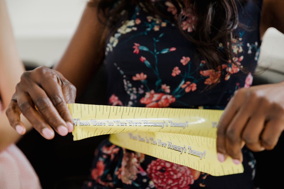 Parent measuring a child at home with a soft tape measure across the shoulders