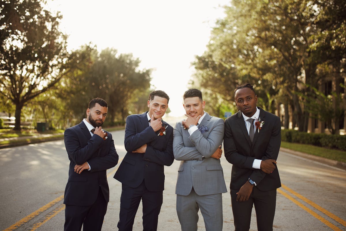 Group of men in tailored suits attending a celebration, smiling and standing together at an outdoor event