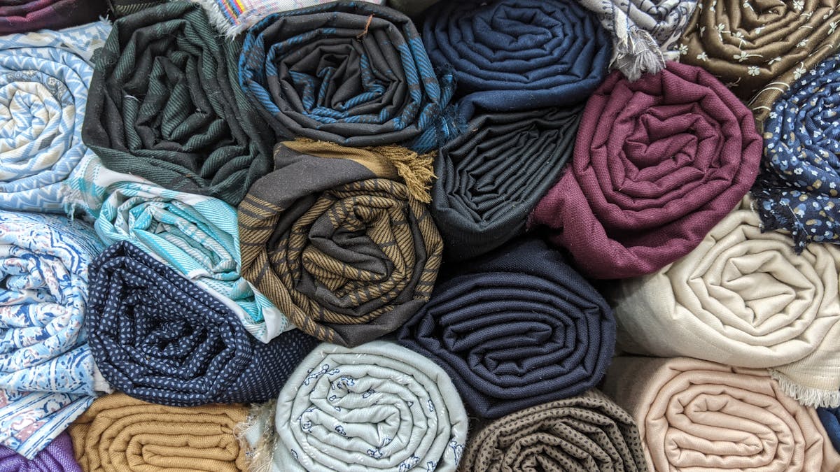 Inside a tailor shop in Hoi An with colorful fabric rolls lining the walls and natural light coming through the entrance