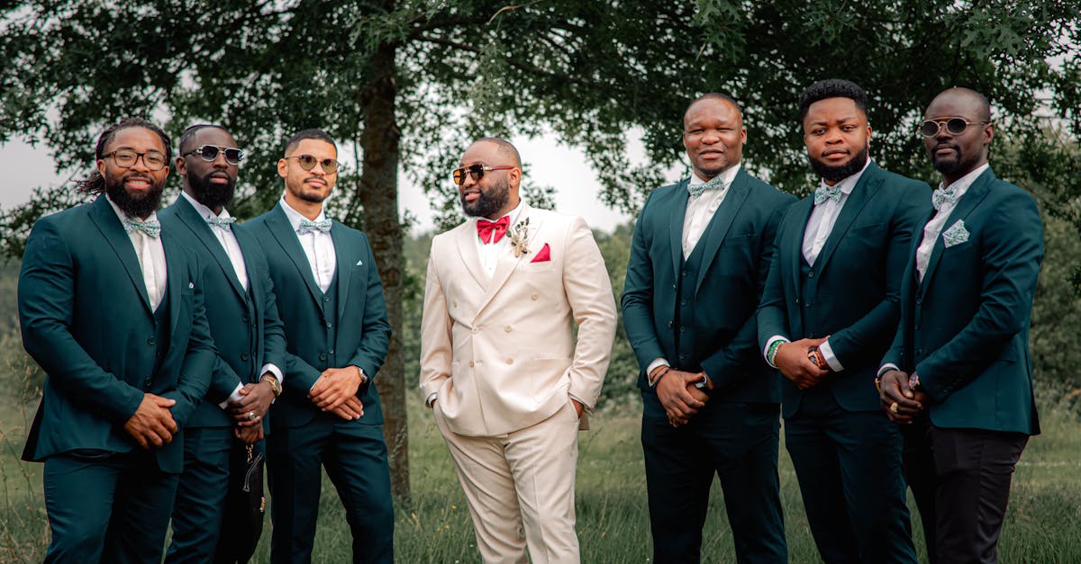 A wedding party of groomsmen in tailored suits, photographed outdoors in coordinated tones.