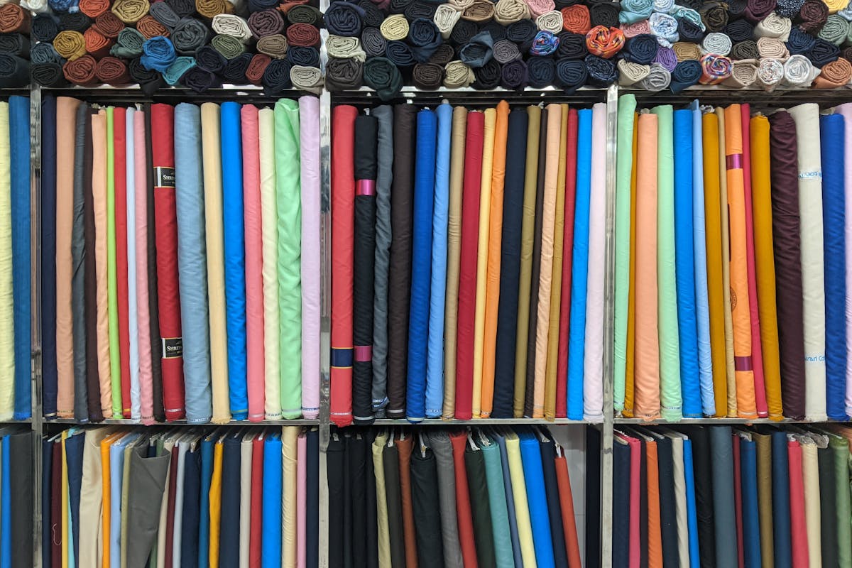 Stacked bolts of wool suiting fabric and colourful swatch cards on a tailor's table in Hoi An