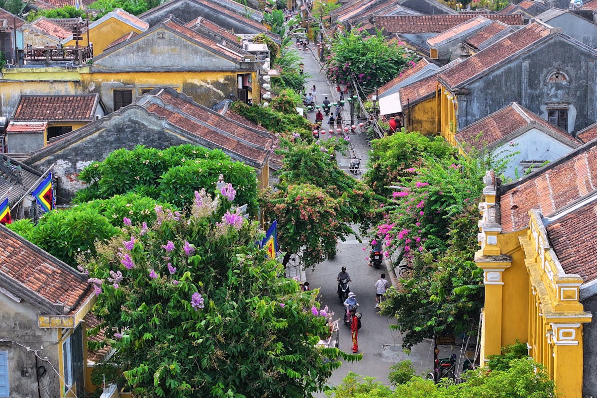 Yellow-walled shophouses and a moss-tiled covered bridge in Hoi An Ancient Town under a clear blue sky