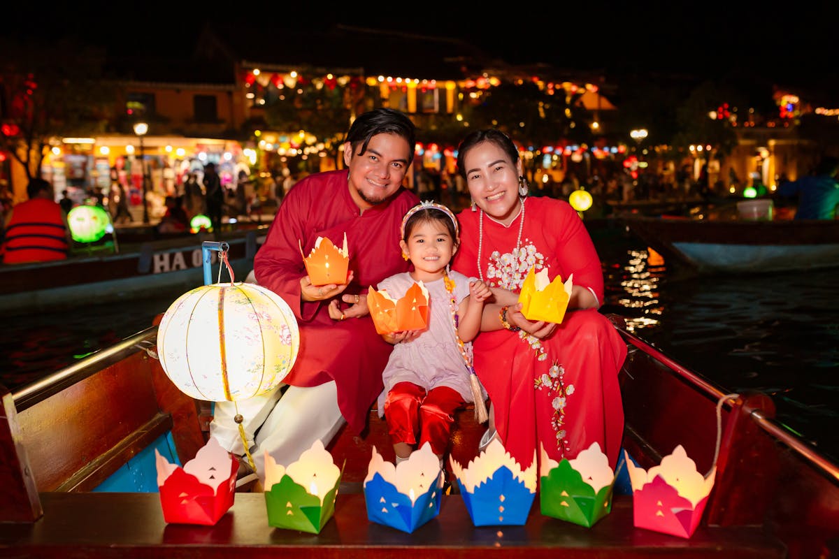 Glowing silk lanterns reflected in the Thu Bon River at night in Hoi An, Vietnam, with tourists releasing paper lanterns onto the water