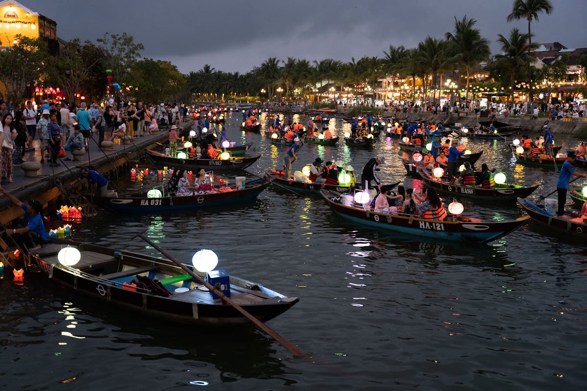 Hoi An Vietnam ancient town at dusk with glowing silk lanterns over a narrow heritage street lined with tailor shops, the UNESCO trading port that has been a textile and tailoring center since the 1600s
