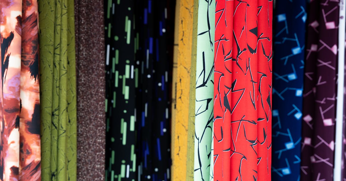 Colorful rolls of cashmere wool linen and silk fabric stacked floor to ceiling inside a Hoi An Vietnam tailor shop where custom suits dresses and garments are made to measure for tourists and visitors