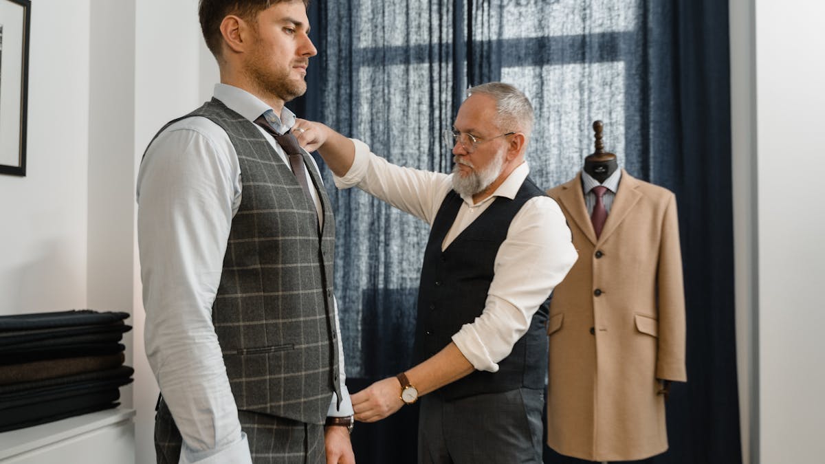 A tailor carefully taking body measurements for a custom suit fitting in an Asian tailor shop