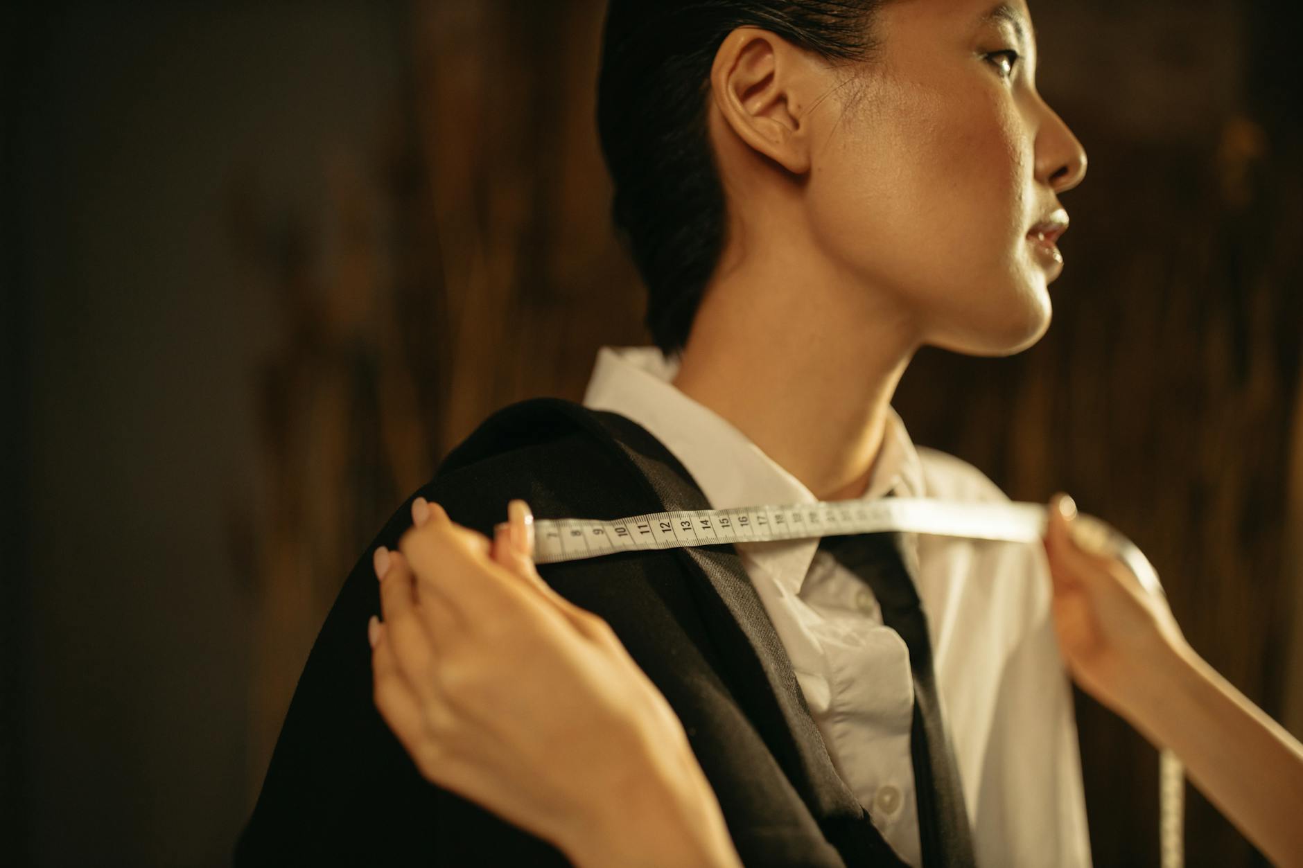 A cloth measuring tape, notebook, and pencil laid out on a wooden surface -- the bare minimum required to measure yourself properly at home