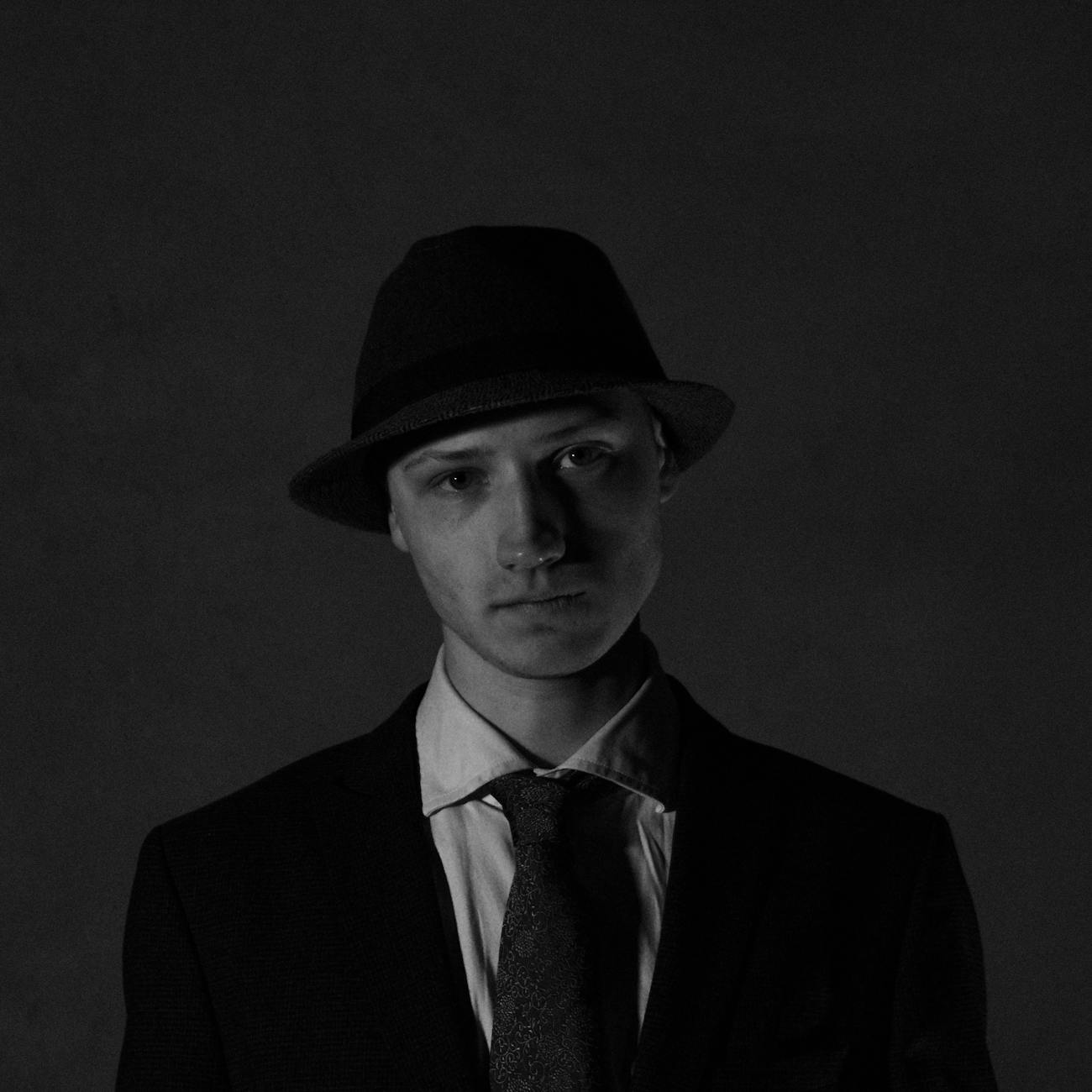 A man in a forest green wool suit with a bow tie and pocket square walks toward the Churchill Downs twin spires on Derby Day