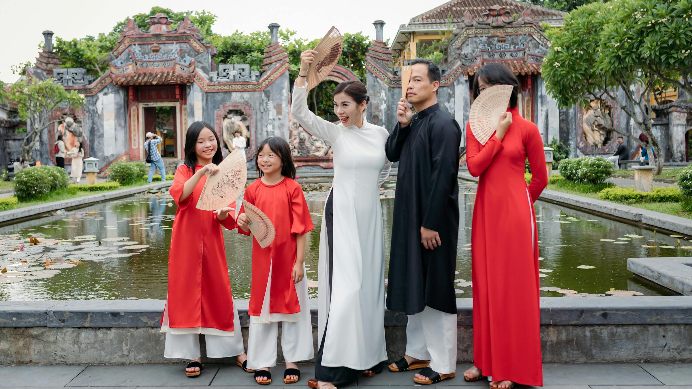 Family wearing matching traditional ao dai at a temple in Hoi An, Vietnam -- the kind of coordinated family photo that becomes a lifelong keepsake