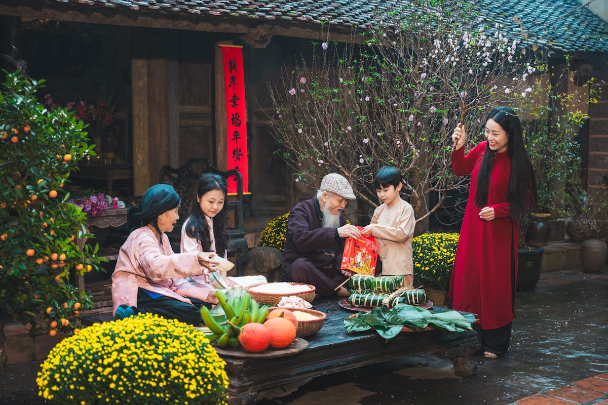 Multi-generational Vietnamese family in coordinated red and gold ao dai posing together for a Tet family portrait