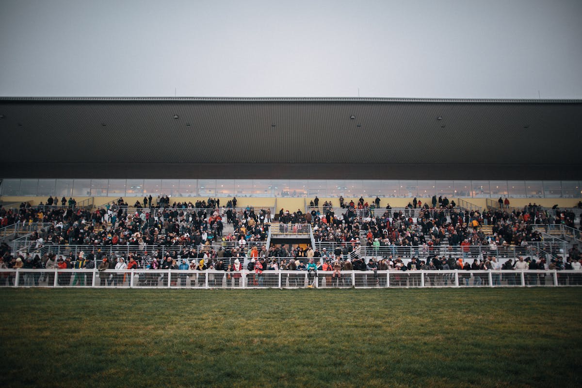 Crowd of well-dressed racegoers at an Australian spring racing carnival, men in suits and women in dresses near the track