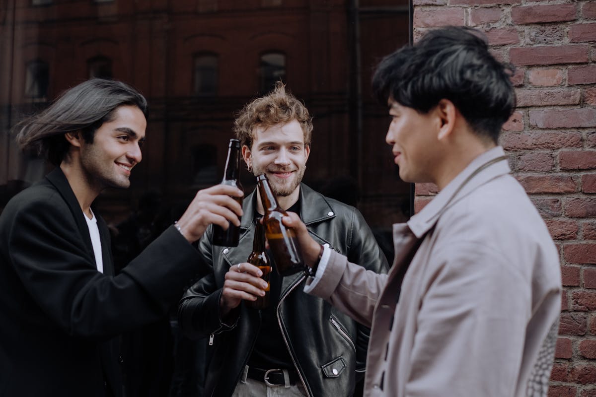 Group of male friends laughing and toasting drinks together on a trip, the boys-trip crowd that ends up getting suits made in Hoi An