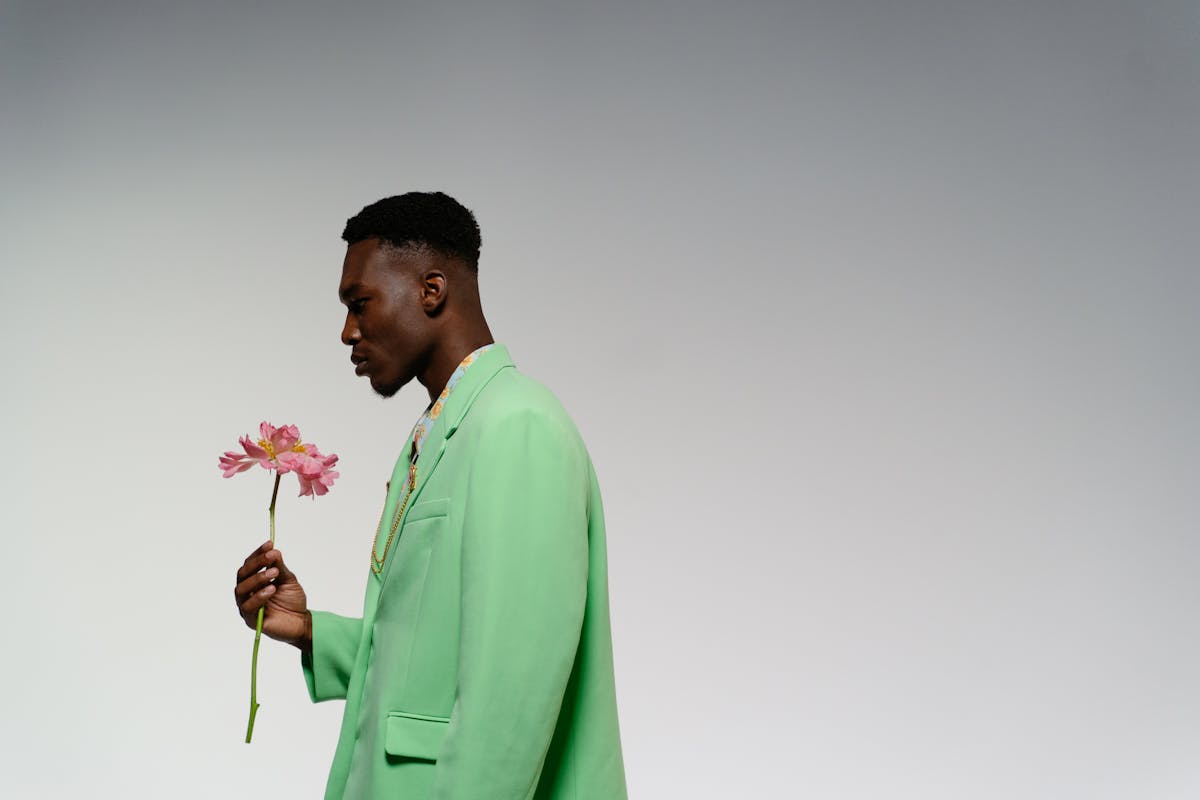 Man in a sage green earth-toned suit standing against a neutral backdrop