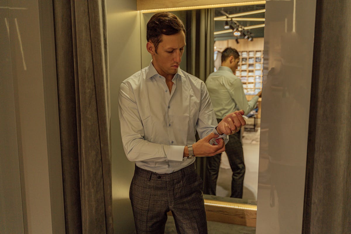 Man in a well-fitted suit checking his reflection in a fitting-room mirror