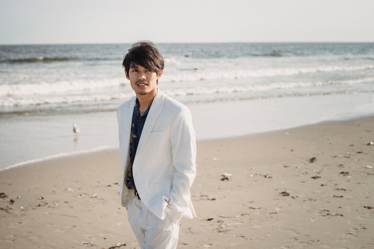 Man wearing a sharp all-white or cream suit outdoors in natural light, showing the monochromatic statement-piece look