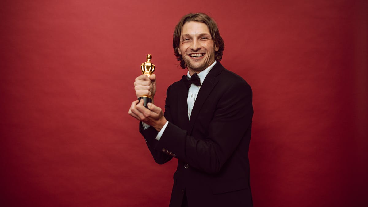 Man in a sharp formal suit against a dramatic red backdrop -- the kind of bold red carpet energy the Met Gala demands