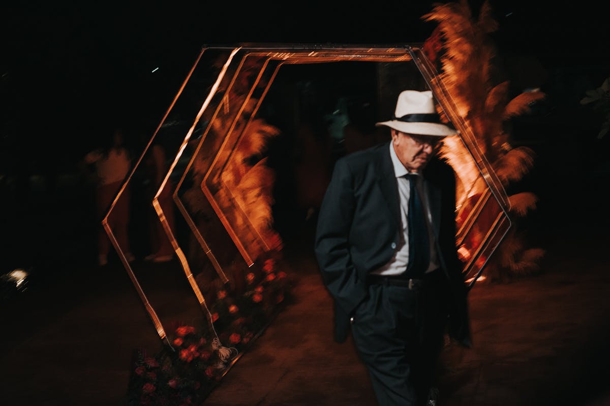Well-dressed man in a dark band-collar suit at an evening event with soft warm lighting