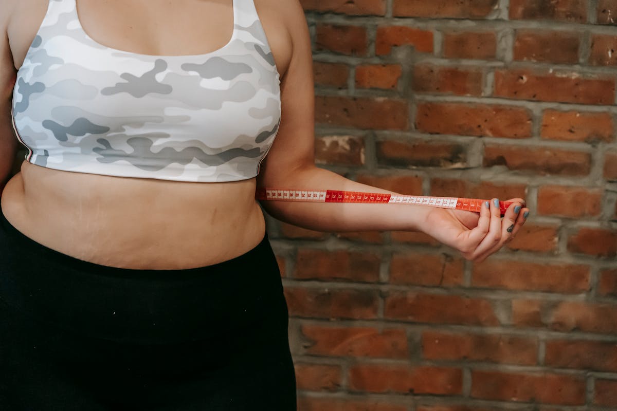 Person measuring their own chest with a tape measure at home next to a phone