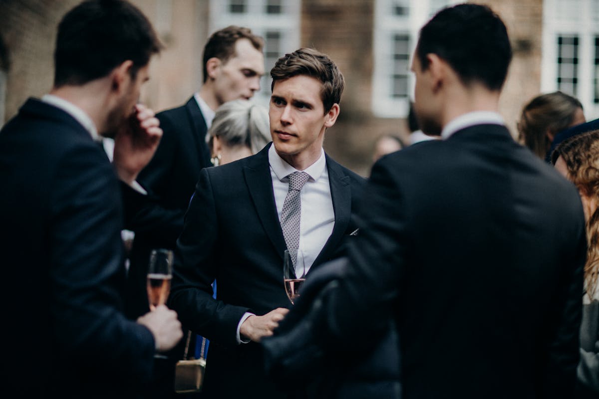 Man in a well-fitted navy suit with a knit tie at a summer wedding reception