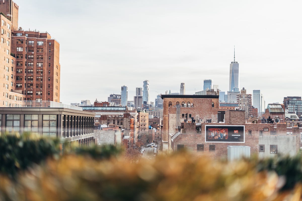 Wedding guests in tailored suits at a New York City rooftop venue at golden hour with the skyline behind them