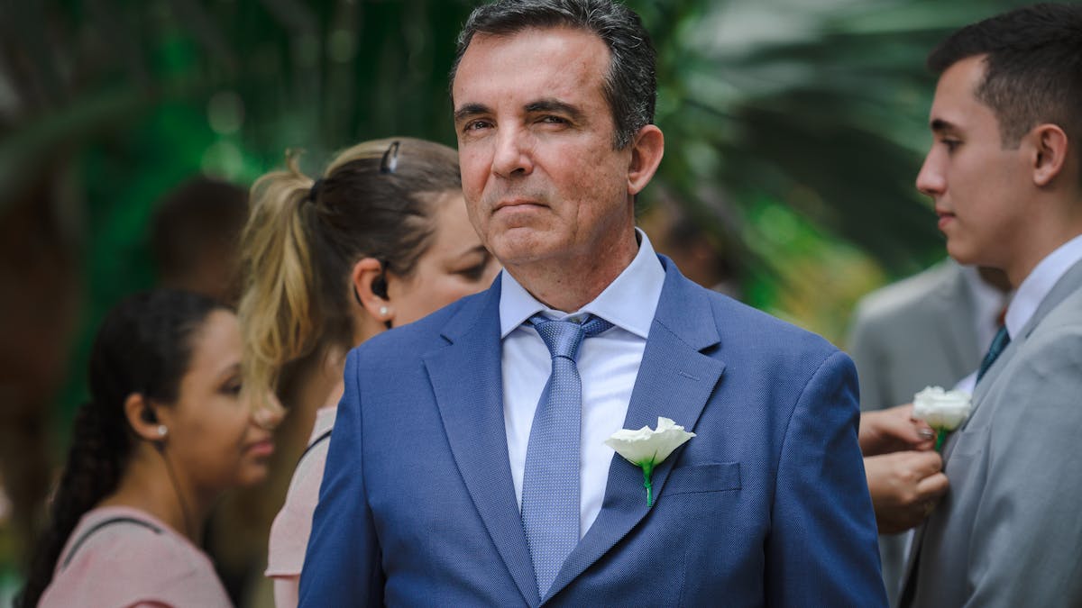 Man in a tailored blue suit at an outdoor summer wedding ceremony