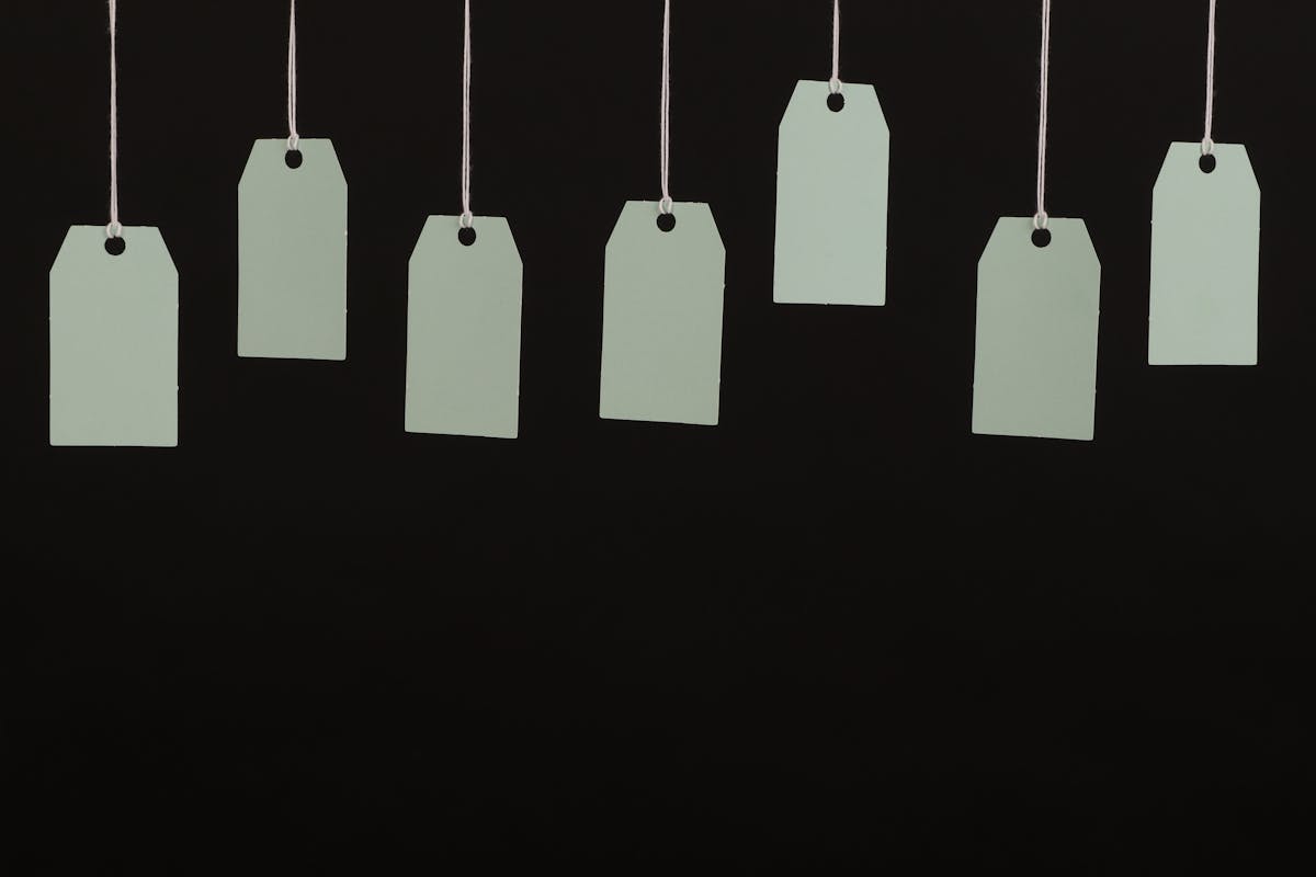Row of formal prom and evening gowns on hangers in a boutique with retail price tags, illustrating designer dress markup