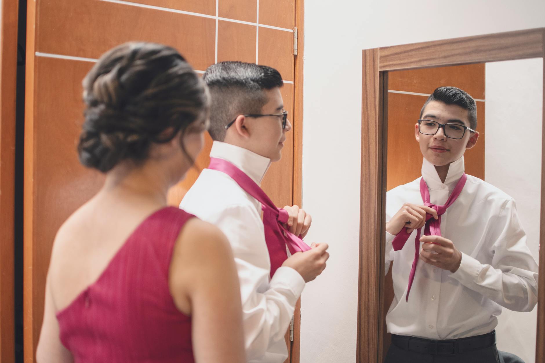 Parent helping teenager adjust tie before prom night